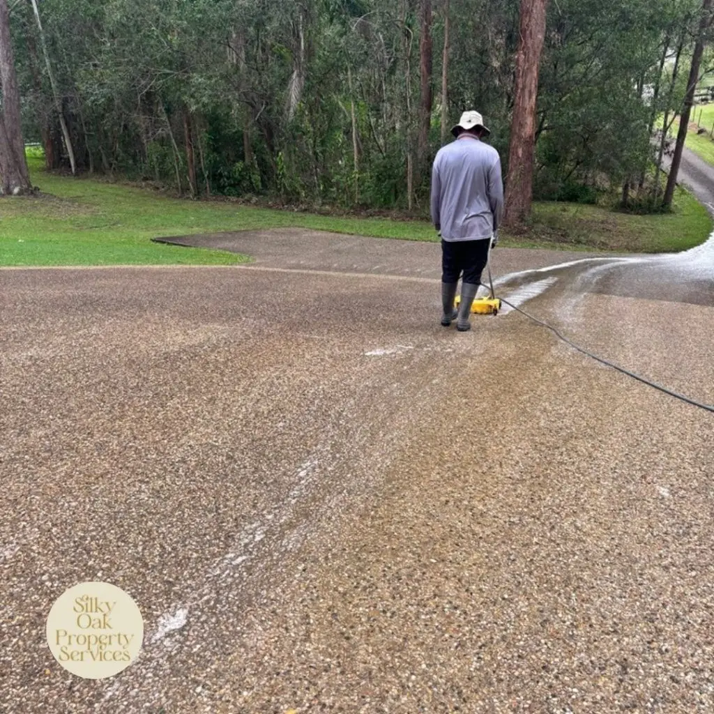Silky Oak Property Services technician pressure washing an exposed aggregate driveway on a strata property in North Brisbane