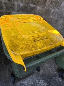 Yellow wheelie bin lid before cleaning